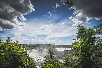 Panoramic View of Iguazu Falls with Lush Jungle and Cloudy Sky
