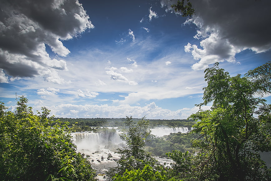 Panoramic View of Iguazu Falls with Lush Jungle and Cloudy Sky