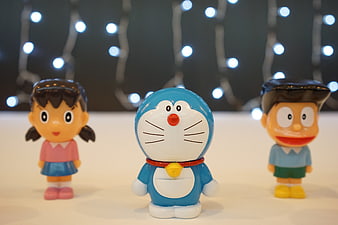 Doraemon, Nobita, and Shizuka figurines with bokeh lights