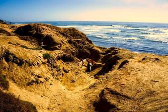 Surfers walking down sandy cliffs to the ocean