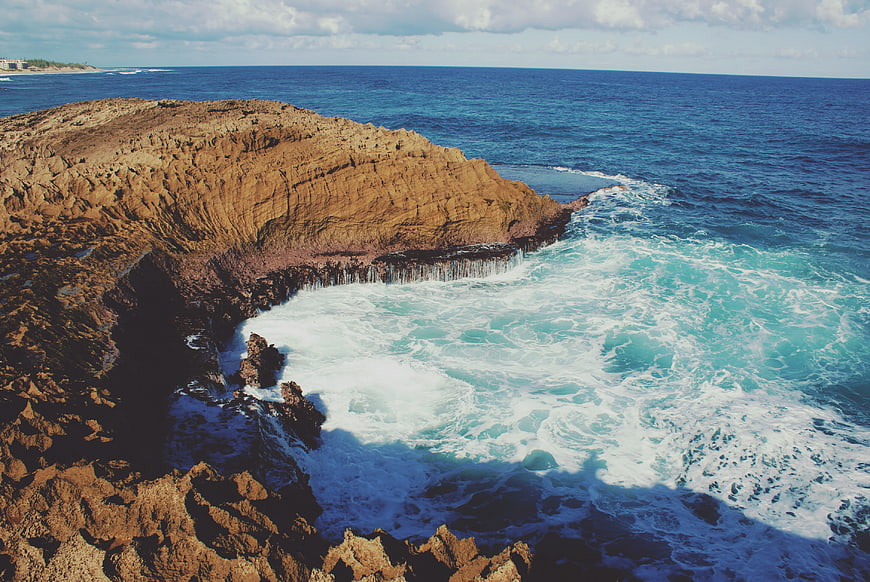 Aerial view of rugged coastal cliffs meeting turquoise ocean waves