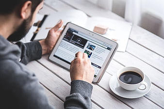 Man using tablet with coffee on wooden table