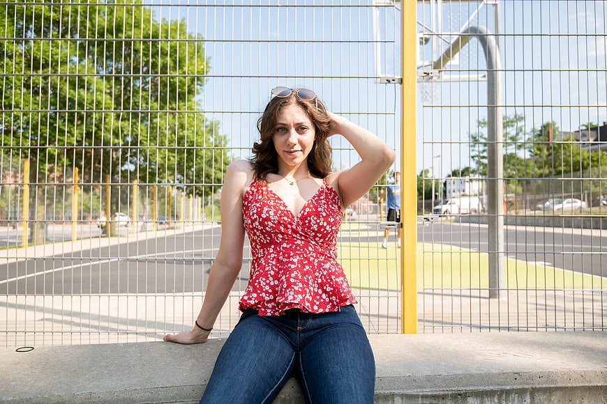 Young woman in red floral top sitting on urban bench