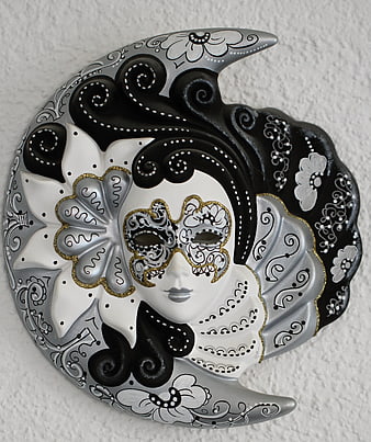 Hand-painted Venetian moon mask with gold accents on textured wall