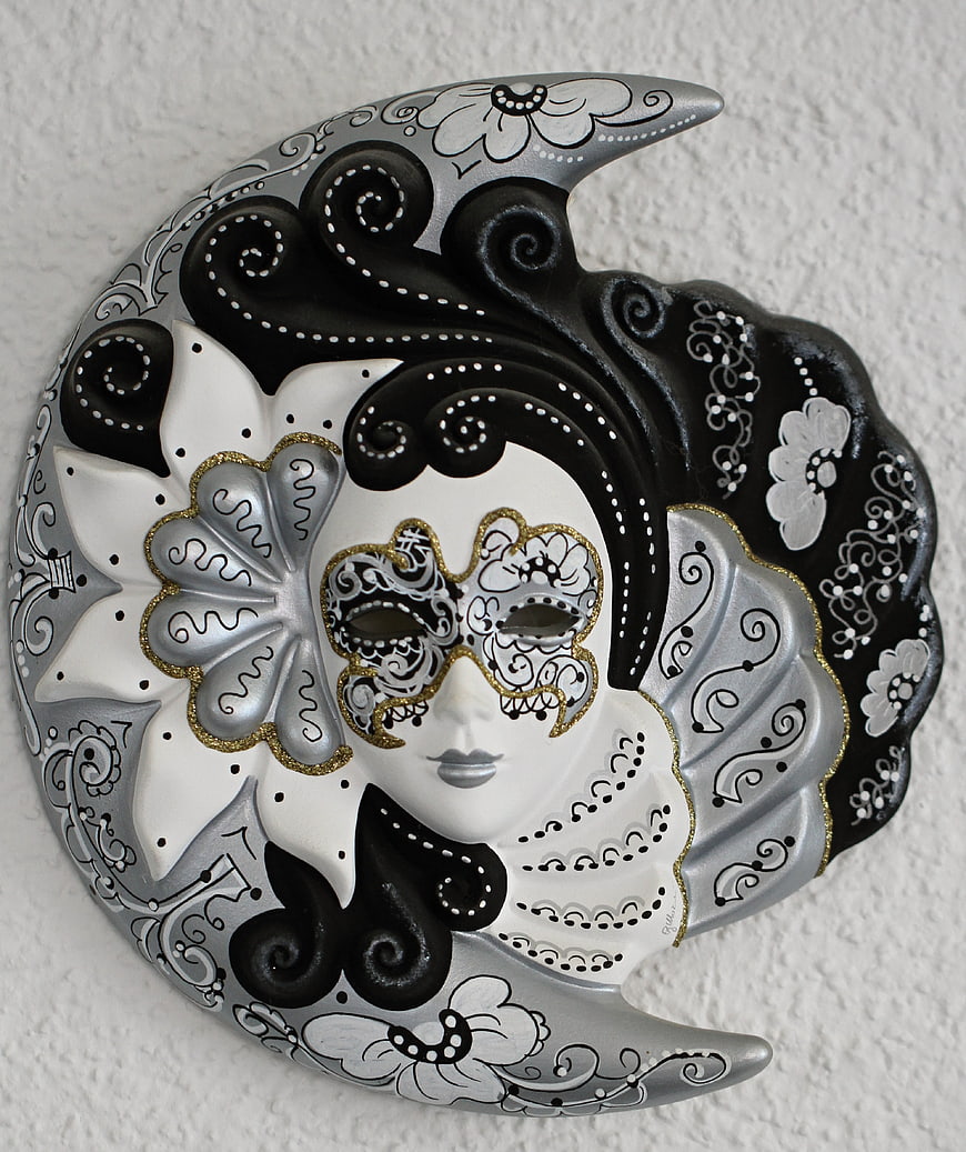 Hand-painted Venetian moon mask with gold accents on textured wall