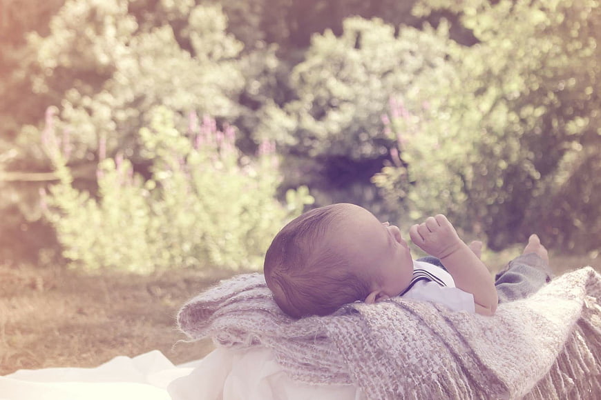 Sleeping newborn baby on knitted blanket in garden