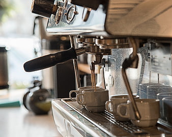 Espresso machine pouring coffee into ceramic cups