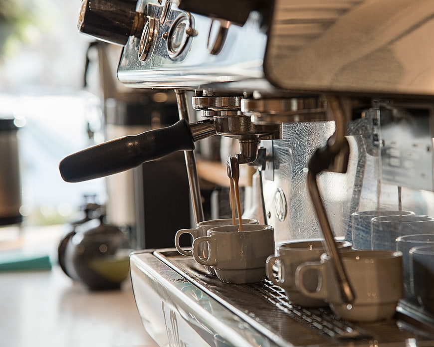 Espresso machine pouring coffee into ceramic cups