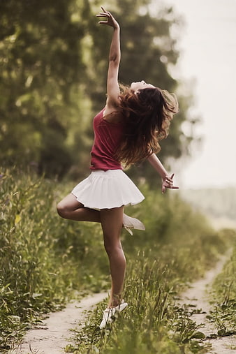 Young woman dancing joyfully on a country path