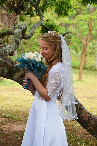 Young woman in white dress holding bouquet outdoors