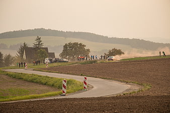 Rally car drifting on rural road kicking up dust