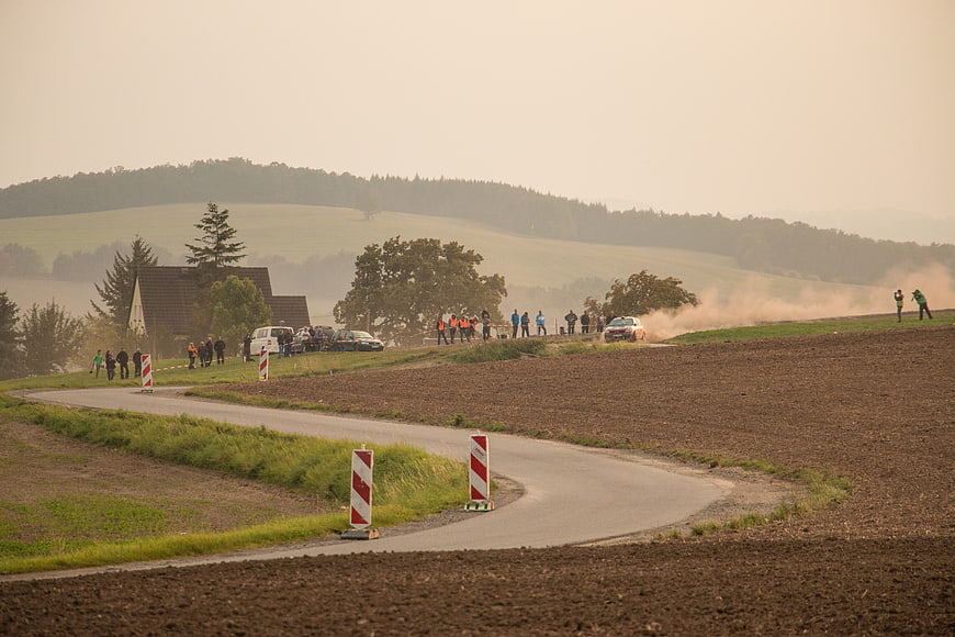 Rally car drifting on rural road kicking up dust