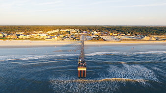 Aerial View of Ocean Pier at Sunset with Beach and Coastal Town