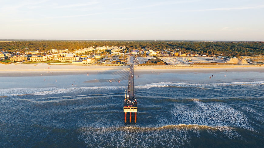 Aerial View of Ocean Pier at Sunset with Beach and Coastal Town