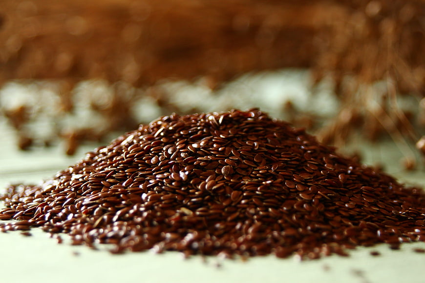 Close-up of brown flaxseed pile on a light surface