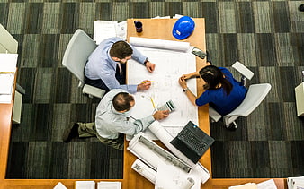 Overhead view of architects collaborating on blueprints in office