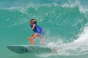 Young boy surfing on turquoise ocean wave