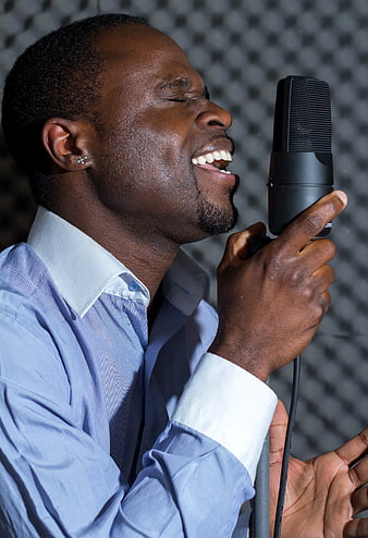 African man singing into microphone in recording studio