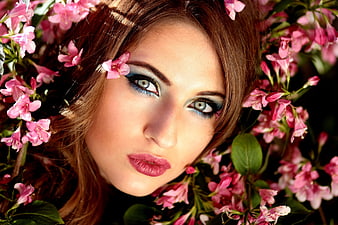 Close-up portrait of woman with blue makeup in pink flowers