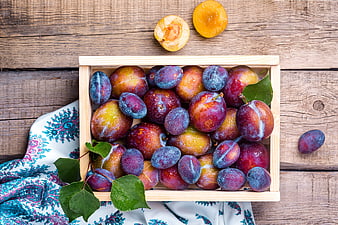 Fresh Summer Plums In Wooden Crate On Rustic Wood Table
