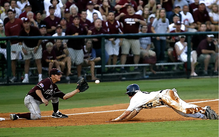 Baseball player sliding into base while fielder catches ball