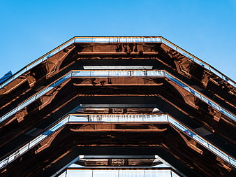 Low angle view of modern geometric architecture against blue sky