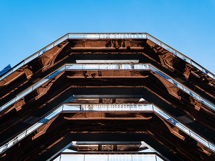 Low angle view of modern geometric architecture against blue sky