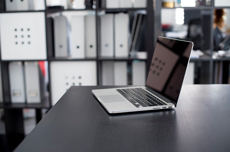 Silver Laptop on Black Desk in Modern Office