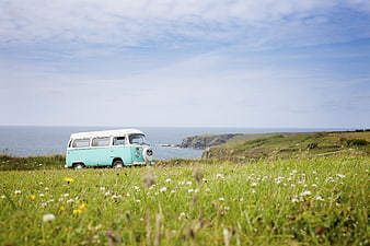 Vintage turquoise VW camper van parked on coastal cliff