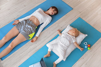 Mother and baby resting on yoga mats at home
