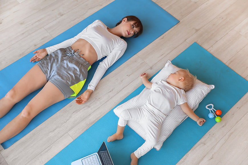 Mother and baby resting on yoga mats at home