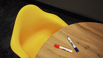 Yellow chair and markers on wooden table in modern office