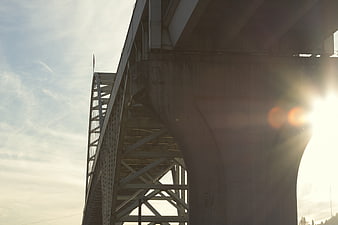 Low angle view of steel bridge structure with sun flare