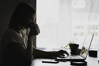 Woman working on laptop by window with coffee
