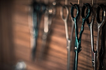 Close-up of hanging barber scissors on wooden wall