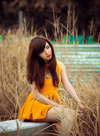 Woman in Yellow Dress Sitting in Tall Dry Grass