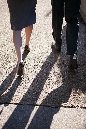 Business Couple Walking Away on Sunlit Pavement