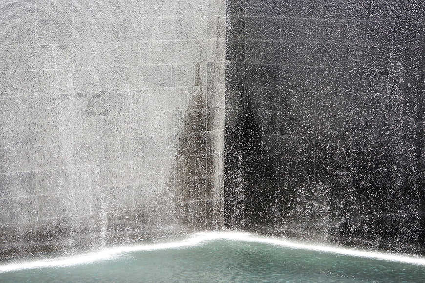 Waterfall cascading over concrete wall into pool