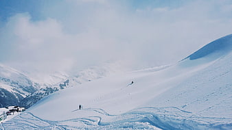 Skiers on vast snowy mountain slope with blue sky