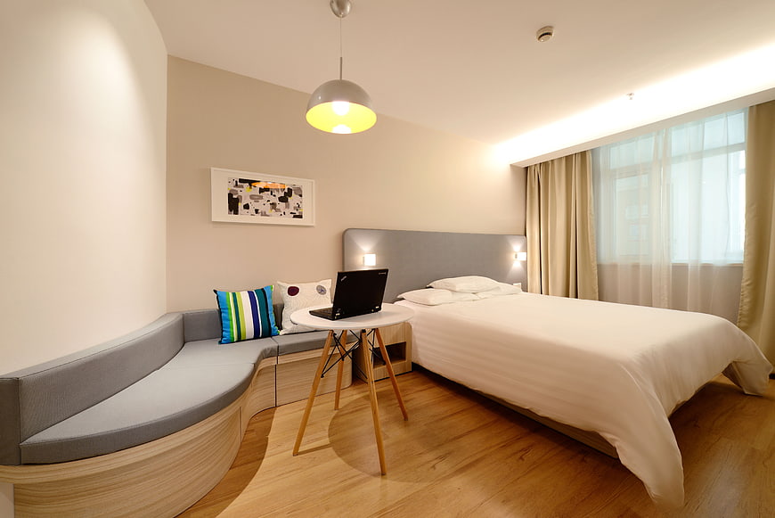 Modern hotel room with curved sofa and laptop workspace