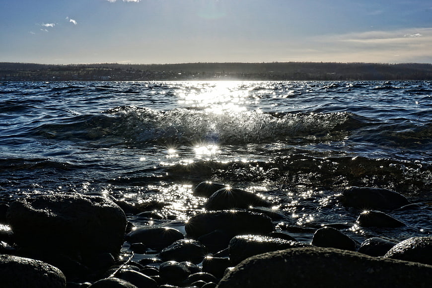 Sunlight Sparkling on Rocky Shoreline with Distant Coast