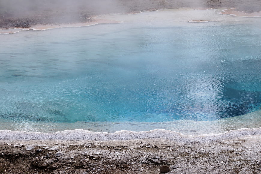 Steaming turquoise hot spring with mineral deposits