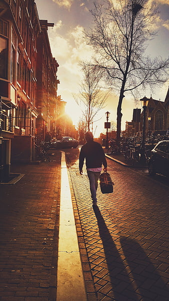 Man Walking Down Cobblestone Street at Golden Hour