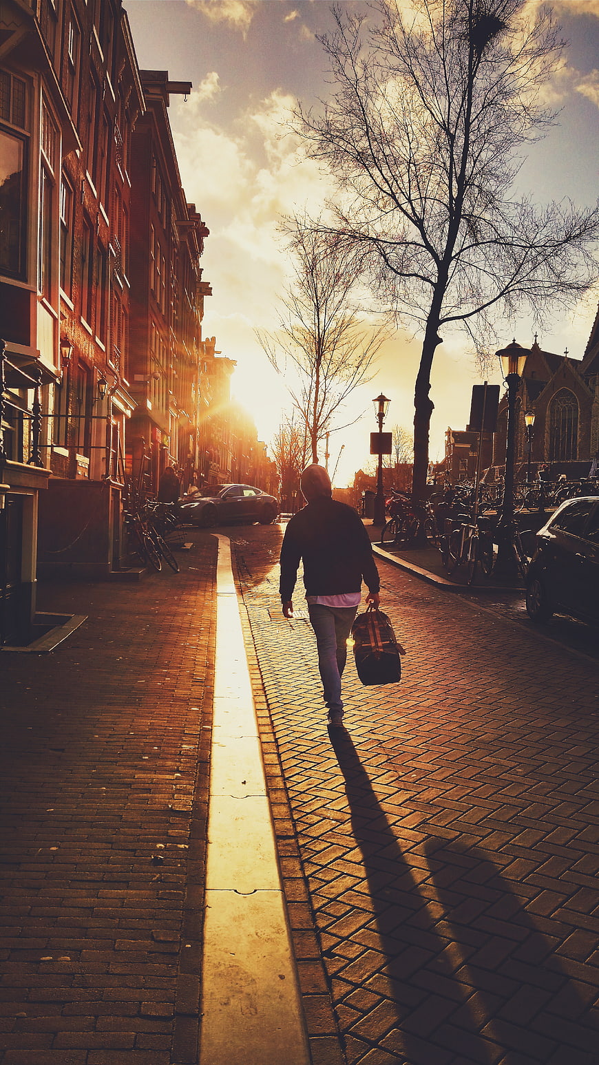 Man Walking Down Cobblestone Street at Golden Hour