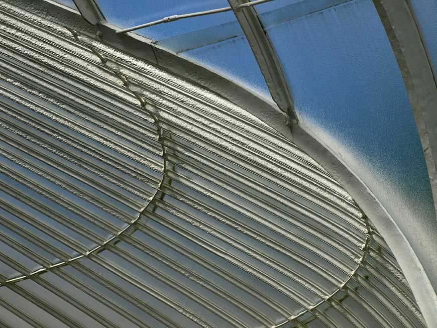 Abstract view of curved corrugated metal roof against blue sky