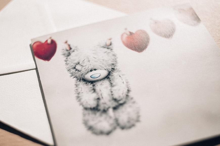 Cute teddy bear illustration on greeting card with hearts