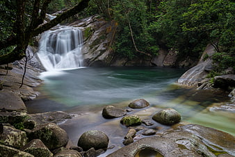Serene waterfall cascading into a misty pool in a lush forest