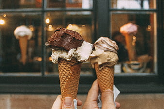 Two Hands Holding Chocolate and Vanilla Ice Cream Cones