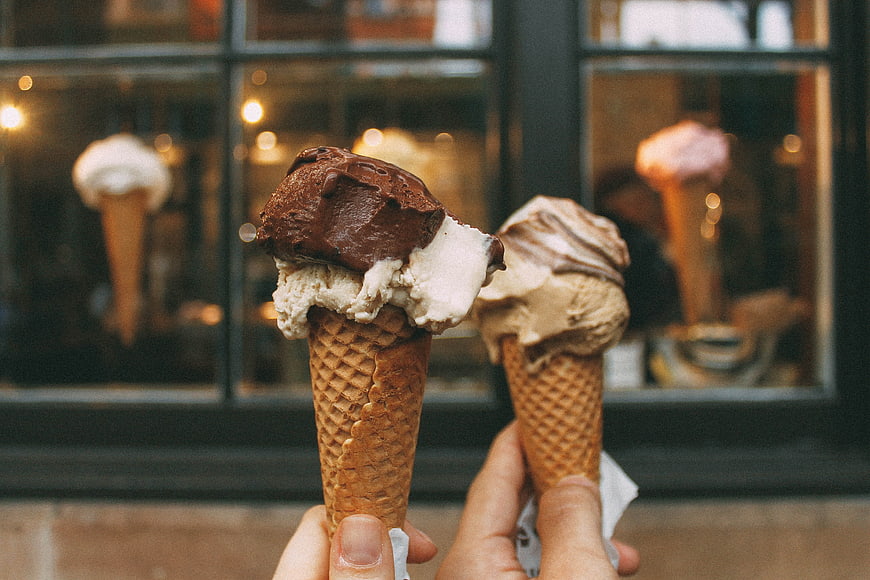 Two Hands Holding Chocolate and Vanilla Ice Cream Cones