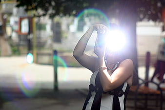 Woman holding camera with bright lens flare